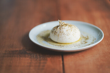 Bufala Mozzarella in center of plate with dressing placed on a wooden table #2