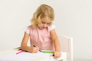 A little girl is drawing at the table.