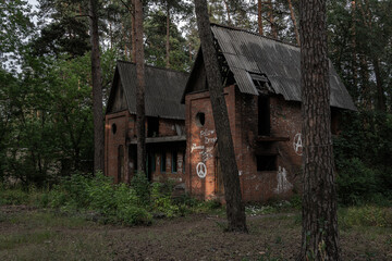 The ruins of an abandoned brick house with graffiti in the forest