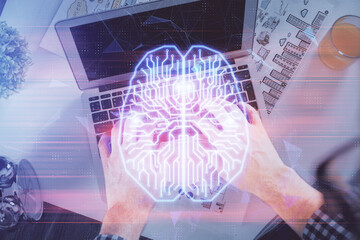 Double exposure of man's hands typing over computer keyboard and brain hologram drawing. Top view....