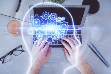 Double exposure of man's hands typing over computer keyboard and brain hologram drawing. Top view....