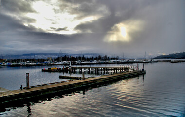 Dock on water with sunshine through clouds