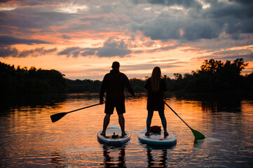 view on couple of people on sup boards on the river at sunset