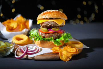 Big hamburger with salad, french fries, onion rings and cheese