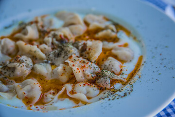 Ravioli - Turkish Manti on plate with red pepper and yoghurt