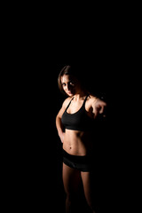 Close up sexy girl shows her perfect body and sports stomach. Healthy fitness and eating lifestyle concept. Fitness sporty woman showing her well trained body, isolated over black background.
