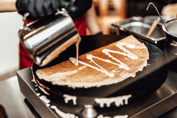 Beautiful and positive brunette woman smiling and working in handmade pancake store. She preparing and serving delicious sweet and salted pancakes.