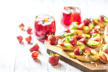 Fresh berry drink on a summer day and bruschetta with strawberries and avocado salsa. Delicious snacks, balanced nutrition.