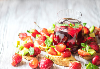 Fresh berry drink on a summer day and bruschetta with strawberries and avocado salsa. Delicious snacks, balanced nutrition.