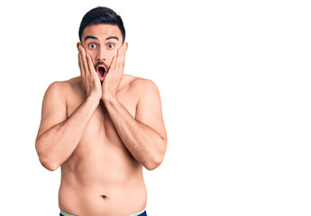 Fototapeta premium Young handsome man wearing swimwear afraid and shocked, surprise and amazed expression with hands on face