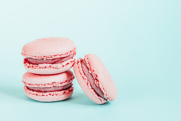 Sweet almond colorful unicorn pink macaron or macaroon dessert cake isolated on trendy blue pastel background. French sweet cookie. Minimal food bakery concept Copy space