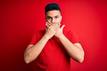 Young handsome man wearing red casual polo standing over isolated background shocked covering mouth with hands for mistake. Secret concept.