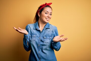 Young beautiful brunette woman wearing casual denim shirt and hair handkerchief clueless and...