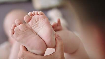 Mother massaging and tickling small baby feet. close up slow motion shot.