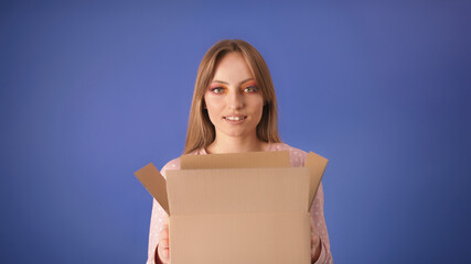 Young caucasian woman with packed cardboard boxes and surprised face isolated on the blue background. Copy space.