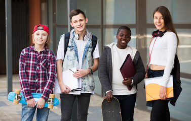 Smiling four friends with folders and backpacks