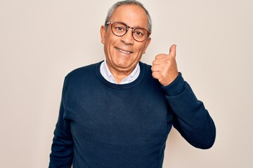 Fototapeta premium Senior handsome grey-haired man wearing sweater and glasses over isolated white background doing happy thumbs up gesture with hand. Approving expression looking at the camera showing success.