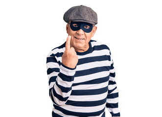 Senior handsome man wearing burglar mask and t-shirt beckoning come here gesture with hand inviting welcoming happy and smiling