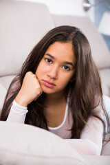 young female sad and thinking on sofa