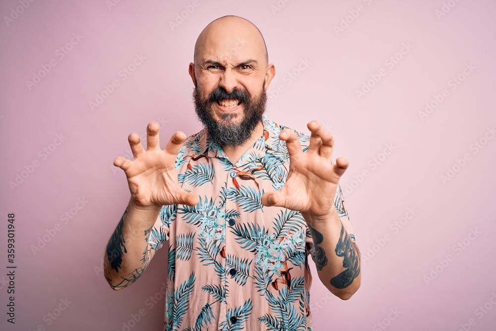 Poster handsome bald man with beard and tattoo wearing casual floral shirt over pink background smiling fun