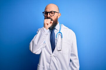 Handsome bald doctor man with beard wearing glasses and stethoscope over blue background feeling unwell and coughing as symptom for cold or bronchitis. Health care concept.