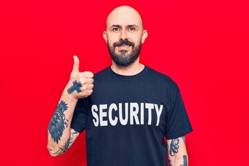 Naklejka premium Young handsome man wearing security t shirt smiling happy and positive, thumb up doing excellent and approval sign