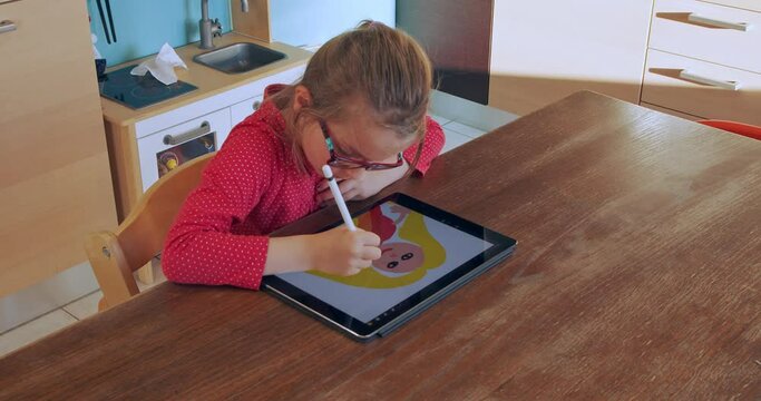 Little girl drawing on tablet at home. Child drawing on tablet device in kitchen on distance education. Girl doing homework on tablet. Smart education. School at home. Distance learning