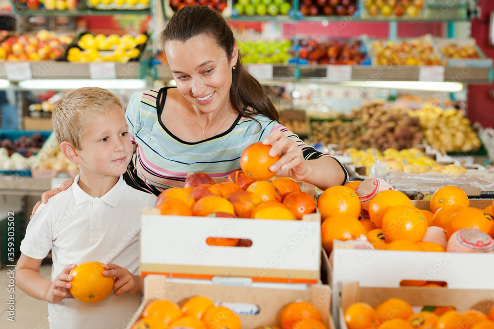 Wall mural son with his mom choosing oranges