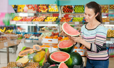 Positive Caucasian female choosing fresh fruits at shop