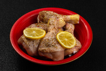 Raw chicken in a red bowl with spices on a black background. Raw meat in the marinade. Dietary meat. Chicken thighs