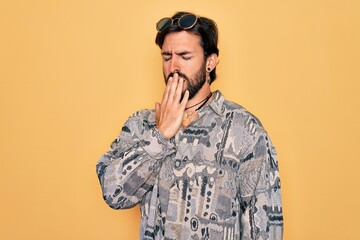 Young handsome hispanic bohemian man wearing hippie style and sunglasses bored yawning tired covering mouth with hand. Restless and sleepiness.