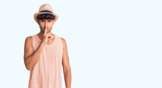 Young hispanic man wearing summer hat asking to be quiet with finger on lips. silence and secret concept.