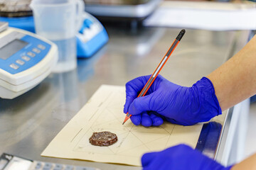 Close up on hands of unknown person wearing protective gloves at the laboratory - Hand with pen...
