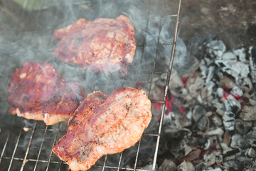 cooking meat over hot coals on a wire rack with a shallow depth of field