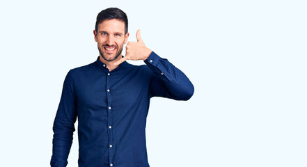 Young handsome man wearing casual shirt smiling doing phone gesture with hand and fingers like talking on the telephone. communicating concepts.