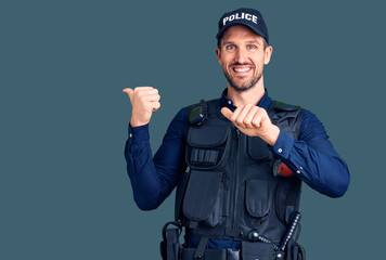 Young handsome man wearing police uniform pointing to the back behind with hand and thumbs up,...