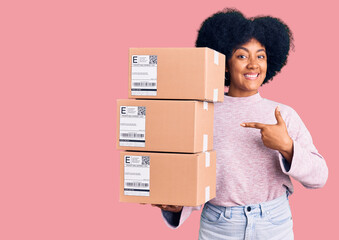 Young african american girl holding delivery package smiling happy pointing with hand and finger