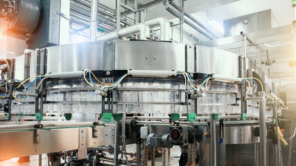Industrial machine conveyor with plastic bottles in beverage factory, industry equipment.