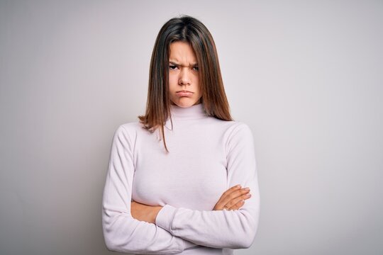Young beautiful brunette girl wearing casual sweater standing over isolated white background skeptic and nervous, disapproving expression on face with crossed arms. Negative person.