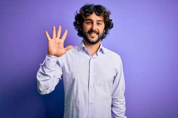 Young handsome business man with beard wearing shirt standing over purple background showing and pointing up with fingers number five while smiling confident and happy.