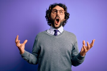 Handsome businessman with beard wearing tie and glasses standing over purple background crazy and...