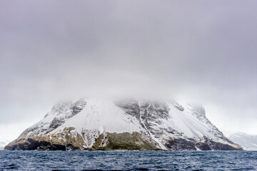 Mountain in snow under the cloud over the ocean