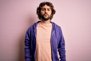 Young handsome sporty man with beard wearing casual sweatshirt over pink background looking at the camera blowing a kiss on air being lovely and sexy. Love expression.