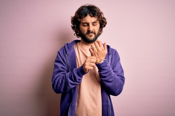 Young handsome sporty man with beard wearing casual sweatshirt over pink background Suffering pain on hands and fingers, arthritis inflammation