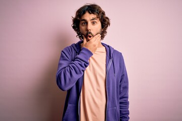 Young handsome sporty man with beard wearing casual sweatshirt over pink background Looking fascinated with disbelief, surprise and amazed expression with hands on chin