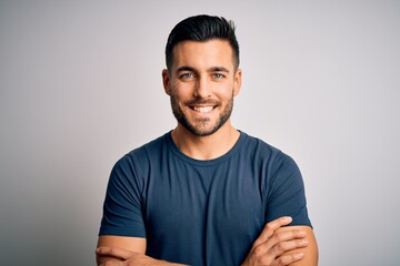 Young handsome man wearing casual t-shirt standing over isolated white background happy face smiling with crossed arms looking at the camera. Positive person.