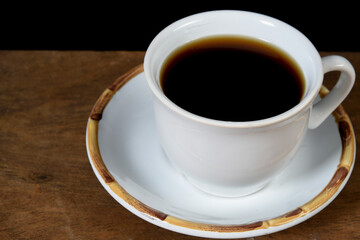 cup with roasted coffee beans inside, on the table with roasted beans top view,.