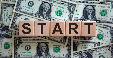 Concept word 'start' on cubes on a beautiful background from dollar bills. Business concept, copy space.