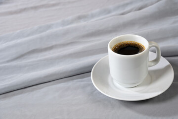 white porcelain cup with coffee isolated on gray cloth with space for text