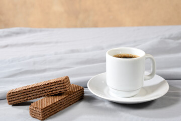 white porcelain cup with coffee and cookies isolated on white cloth with space for text